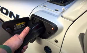 Image of James standing next to his Jeep Wrangler 4xe, which is connected to a Jeep Smart Charging Station. The charging cable is plugged into his Jeep 4xe.